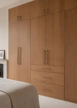 Bespoke fitted cupboards with natural wood finish, tall storage and built-in drawers