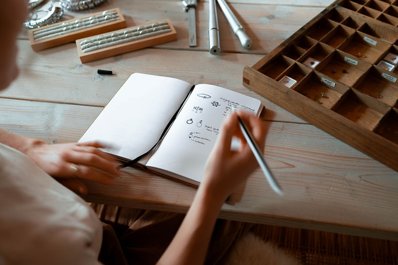 Isabel schetst ontwerpen voor ringen in een notitieboek