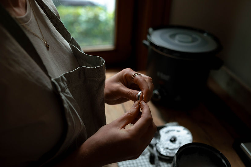 Isabels handen houden een zilveren ring vast in haar atelier