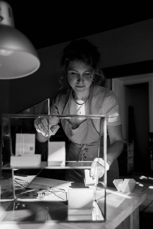 Isabel zet juwelendoosjes in een glazen vitrine in haar atelier