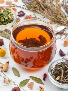 Xícara de chá artesanal cercada por folhas secas e ervas aromáticas, representando o retorno do chá como tendência global de bem-estar.