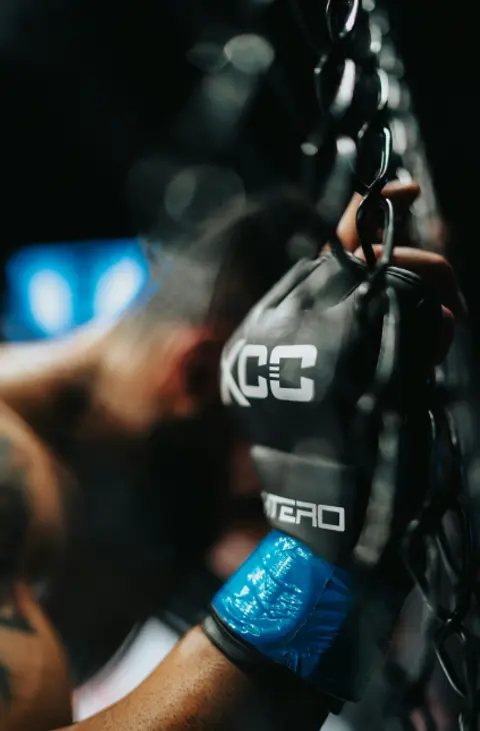 Mixed Martial Artist recovering by leaning on the cage at Wu Xing Dao Kung Fu