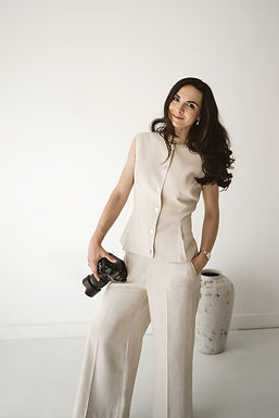 Roxana, wedding photographer behind LaRoux Wedding Photography, smiling while holding a camera.