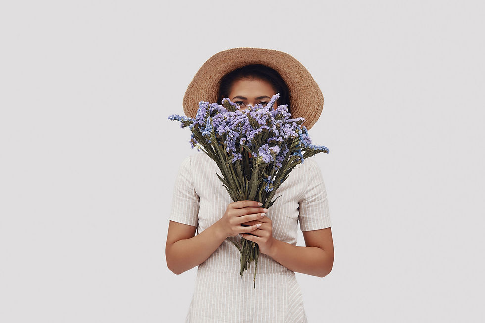 Woman wearing hat covering her face with a bouquet