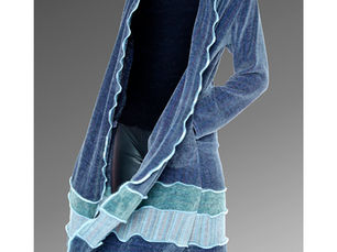 A women walking on the beach wearing a handwoven coat by The Oregon Weaver.
