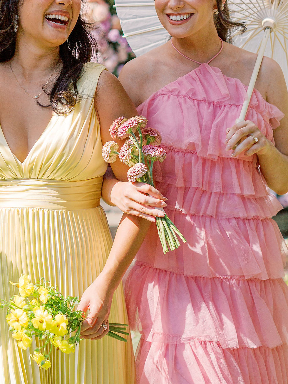 Bridesmaids in mismatched pastel Revelry bridesmaid dresses at a garden wedding.