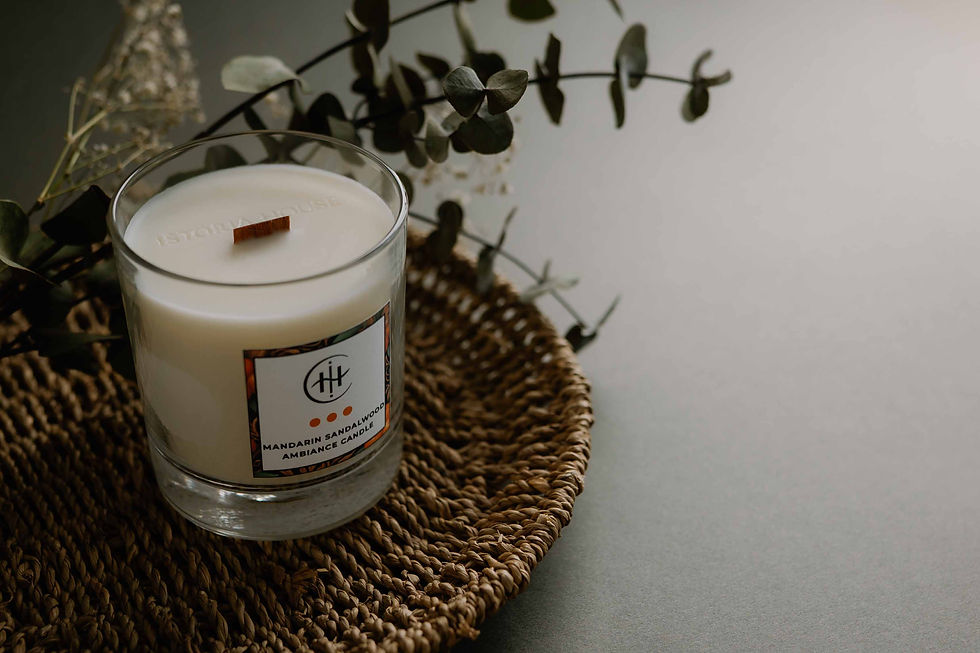 Amber Pomegranate luxury candle in clear glass, styled with eucalyptus on a woven placemat