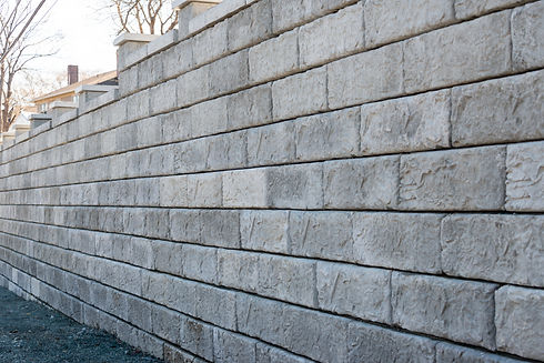 A large grey precast concrete block wall. The massive rectangle shaped bricks are interloc