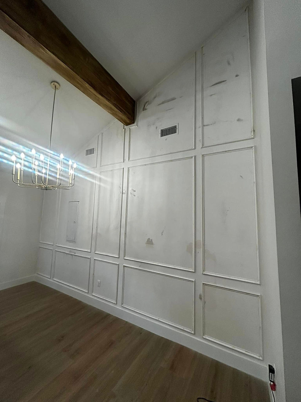 White room with board-and-batten wall paneling, exposed beam and wood floor