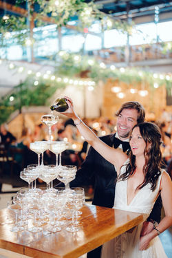 couple pouring champagne into champagne glass tower