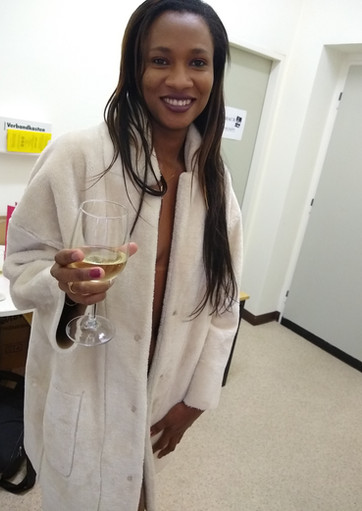 Elegante Frau im weißen Bademantel hält ein Sektglas.