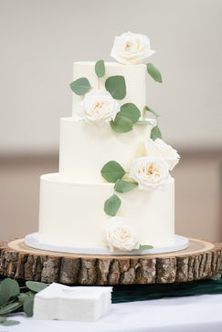 three tiered wedding cake with smooth buttercream and fresh flowers and greenery