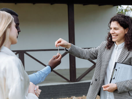 An estate agent smiles as she hands house keys to a new home-owning couple in South East London on their completion day.