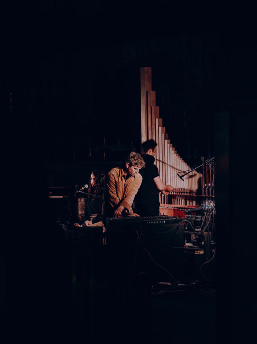 3 musicians play their instruments inside a church in montreal with moody lighting