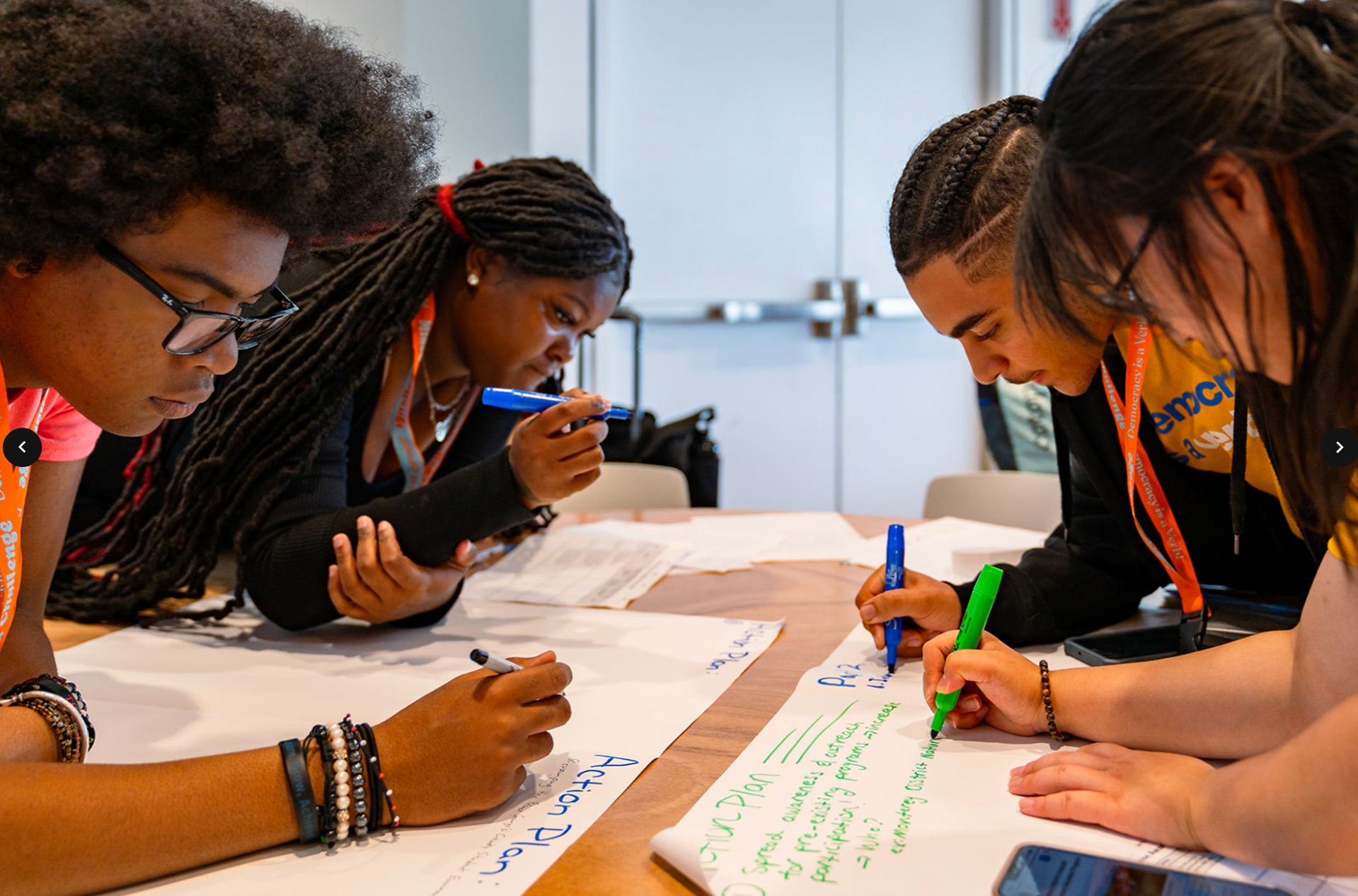 A group of students writing with markers on paper.