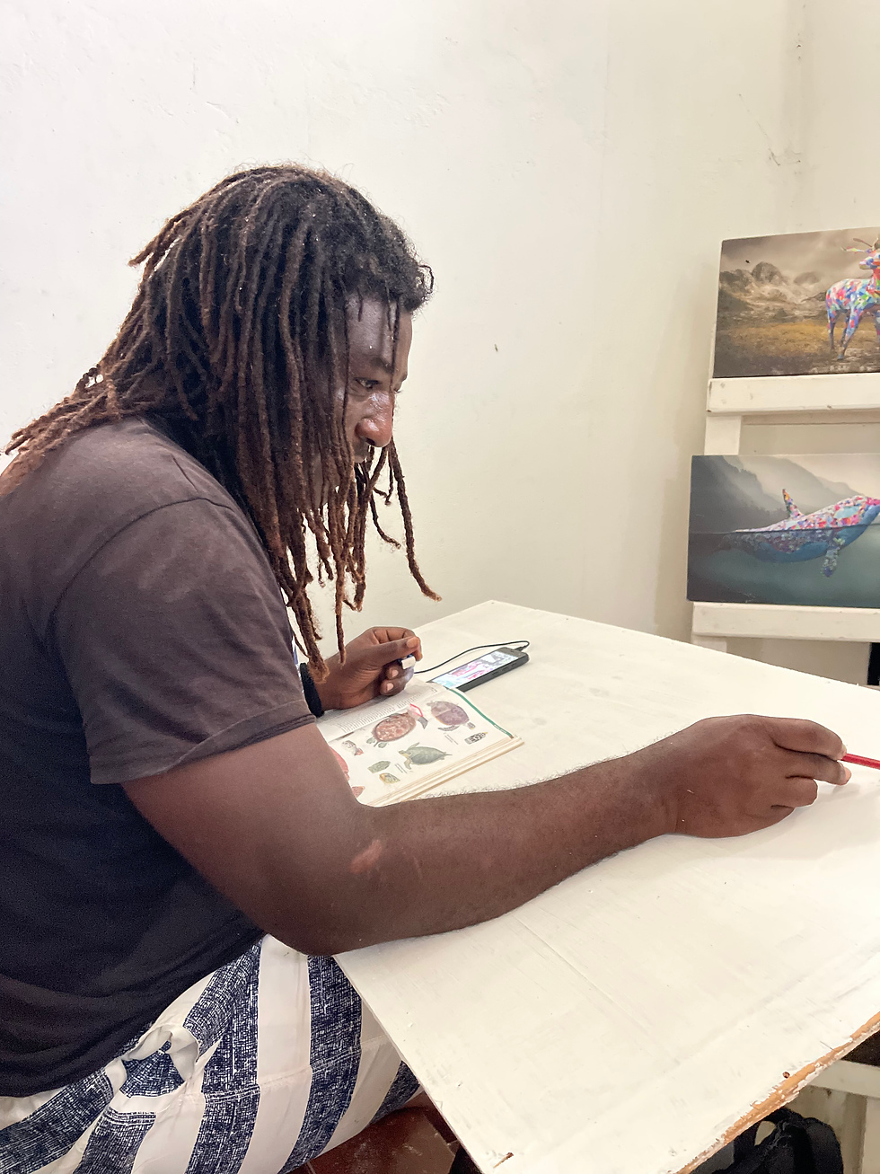 Turtle ranger Omar sketches turtle outlines on paper to guide schoolchildren in conservation-themed art projects.