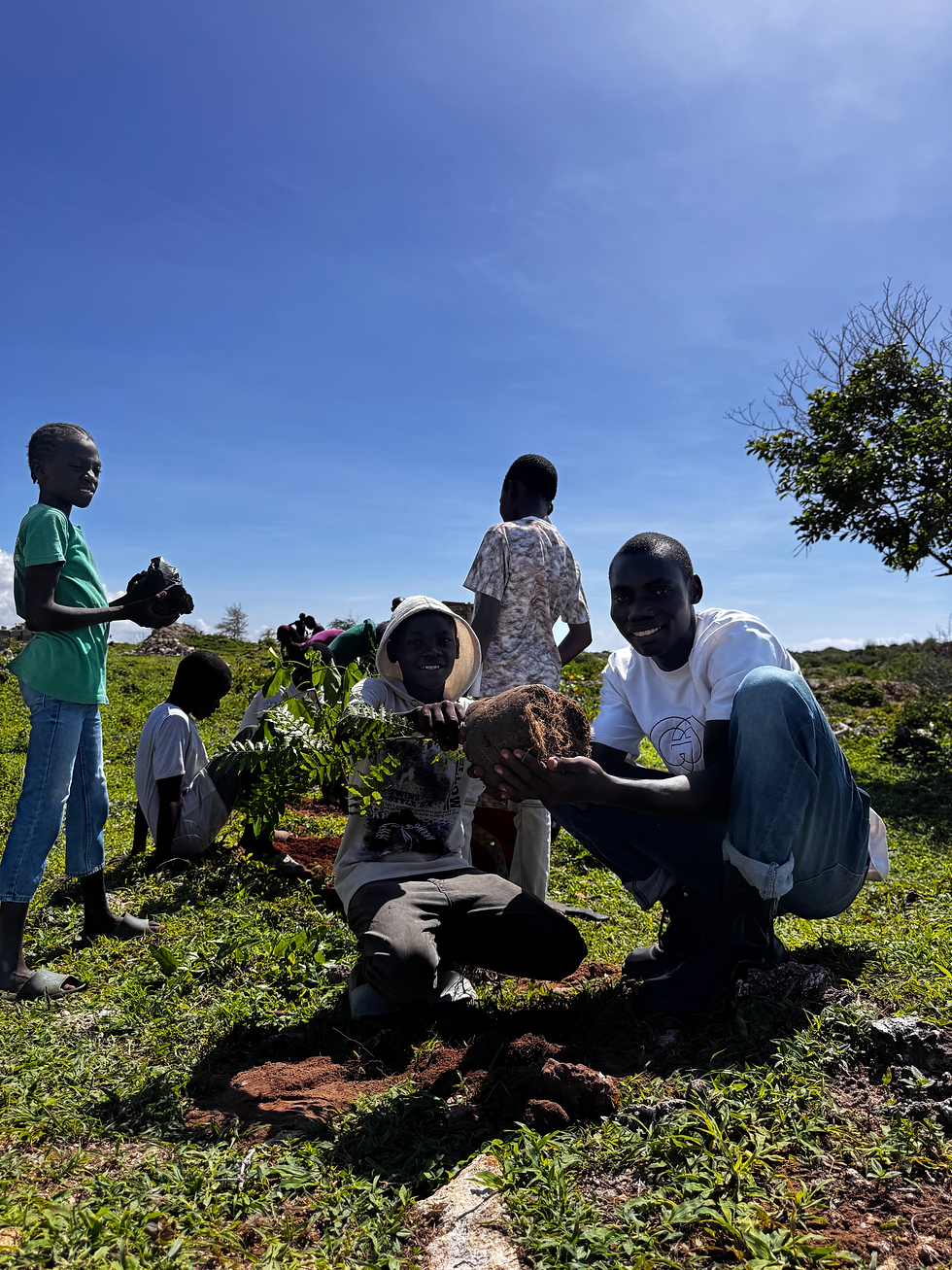 Two boys from the orphanage smile and cheer as they prepare to plant a tree during a conservation day supported by Ocean Sole.
