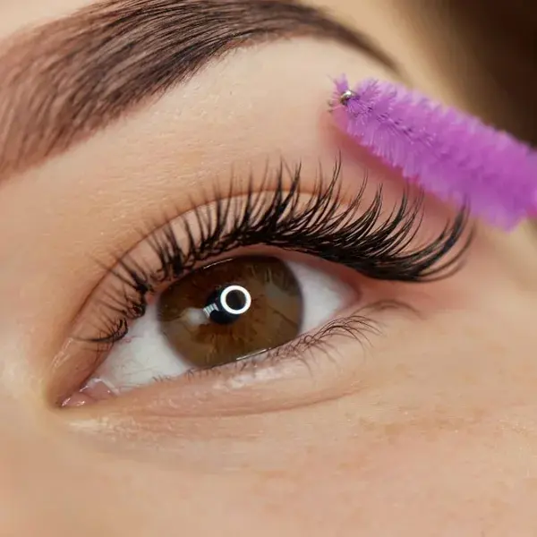 Close-up of eye with Wimpernverlängerung One by One Neuanlage, brush, long lashes.