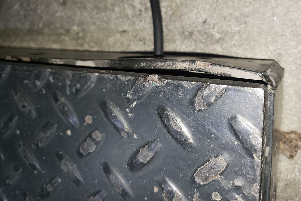 A floor scale that is scratched and dented on its side.