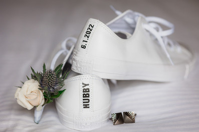 flatlay of delicate wedding details and converse shoes