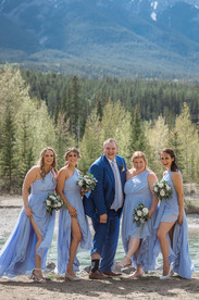 groom posing with bridesmaids laughing