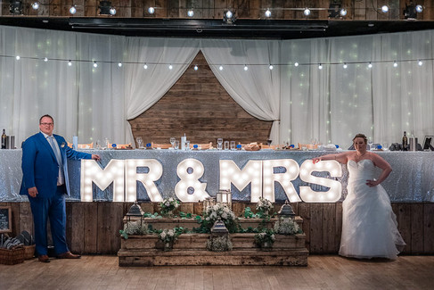 bride and groom posing next Mr and Mrs sign at reception