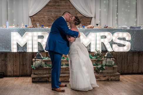 bride and groom hugging in front of Mr and Mrs wedding sign