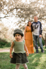 Baby girl gazing at the camera with mom and dad looking on in the background