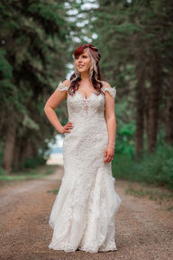 portrait of bride standing in the middle of tree lined dirt road