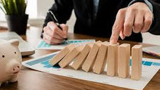 Businessperson stopping falling dominoes, symbolising risk management and control.