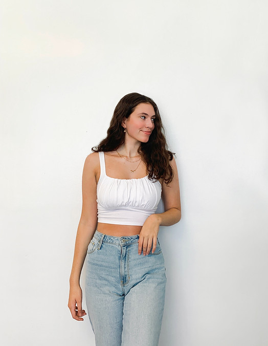Chloe standing, smiling agaisnt a white wall