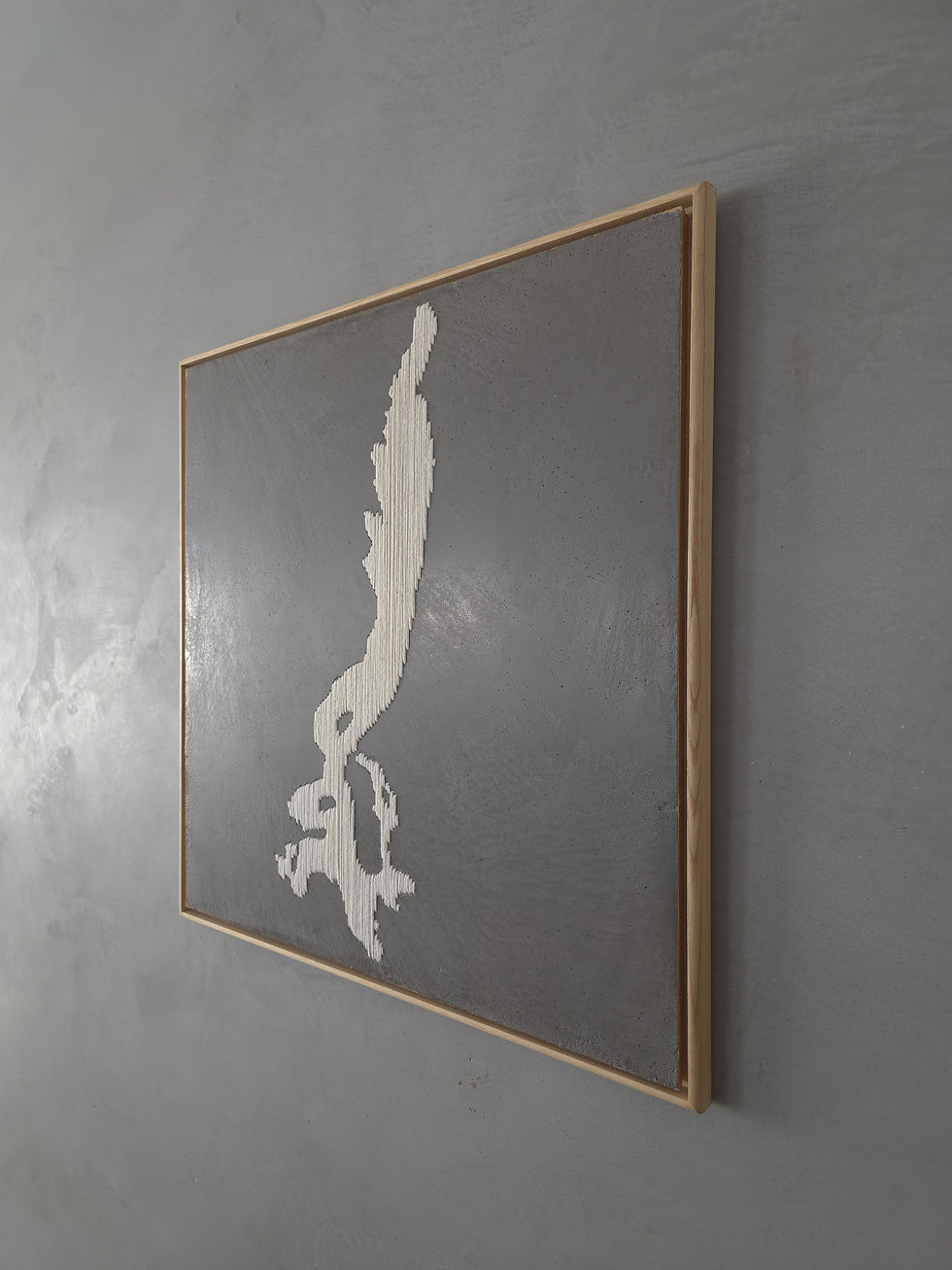 Angled view of framed artwork on grey wall.