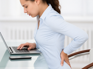Person sitting hunched at a desk with visible tension in neck and shoulders – great example of neck and shoulder pain common among Austin desk workers.