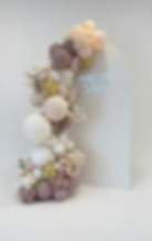 A neutral backdrop panel reading 'MAZEL TOV Stella', framed by an organic balloon garland with delicate floral accents