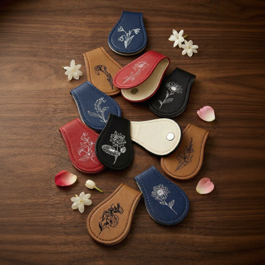 Red engraved floral magnetic bookmark on an open book next to a latte in a cafe window.