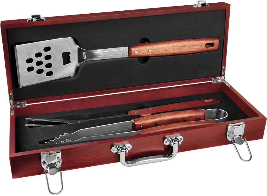 Open rosewood case displaying stainless steel spatula, fork, and tongs in foam, ready for custom engraving.
