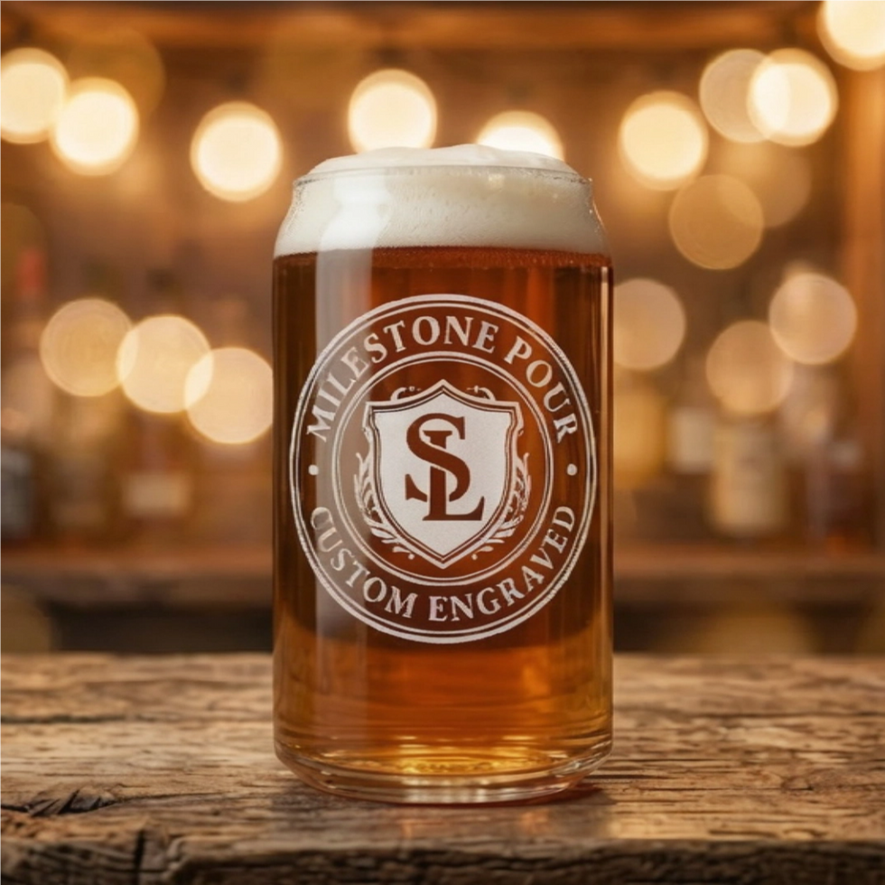 Custom laser engraved beer can glass featuring a 'Milestone Pour' shield logo, sitting on a rustic wooden bar top with warm b