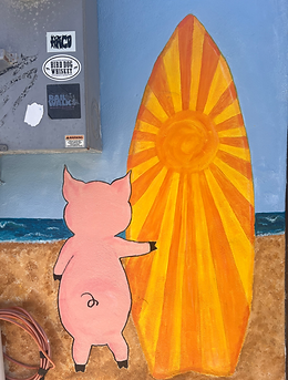 Part of the mural with a pig and his surf board walking to the ocean.