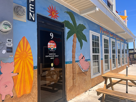 Sunny Daze mural, full view of pigs on the beach and lettering stating "Piggin' out at Sunny Daze".