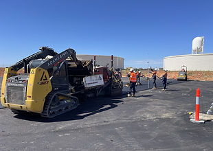 Adams Civil skid steer working on an asphalt tank floor