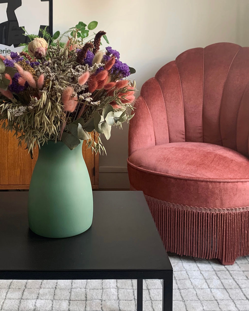 Un fauteuil crapaud velours rose chiné et un bouquet de fleur séchées sur la table basse