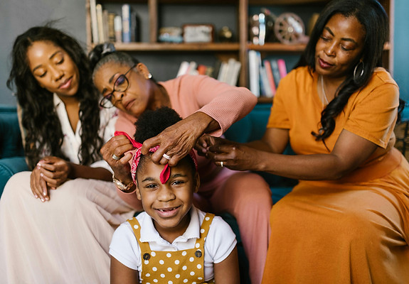 a family photo of three generations of women sitting playfully on the couch