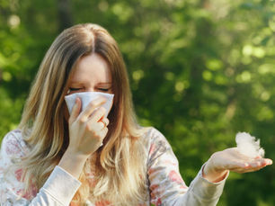 Frau mit Heuschnupfen hält Taschentuch und reagiert auf Pollen im Frühling