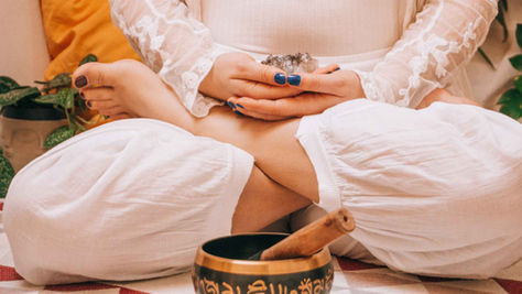 Frau meditiert mit Klangschale – Sakralchakra Aktivierung im Unterbauchbereich