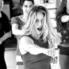 Femme projetant un puissant coup de poing Outward Punch devant elle et poussant un cri de rage. Deviens Femme confiante, combative, puissante, ancrée et souveraine de ton propre corps grâce à la Danse, aux Arts Martiaux et à l'Energie de ton Souffle, de ta Voix.