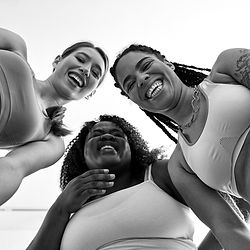 Trois femmes de morphologies et d'origines différentes en tenue de sport aux sourires éclatants après leur cours de danse collectifs OHM experience.