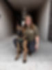 Smiling woman kneels with her Belgian Malinois dog indoors.