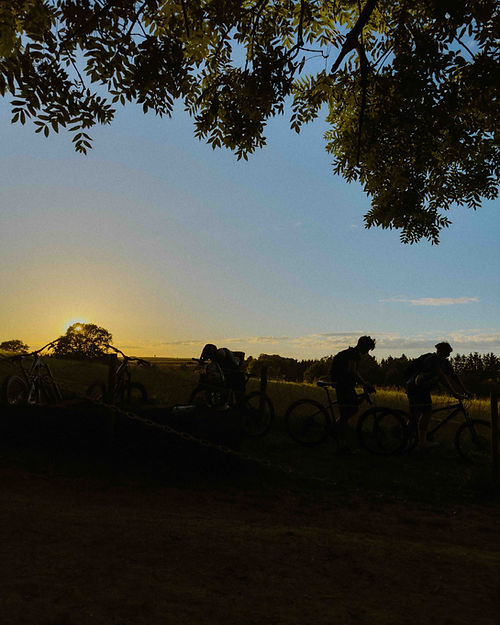 Some riders at sun down on the mountain bike trail with their bikes