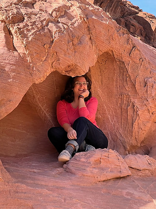 Eliza sits in the hollow of a red rock formation.