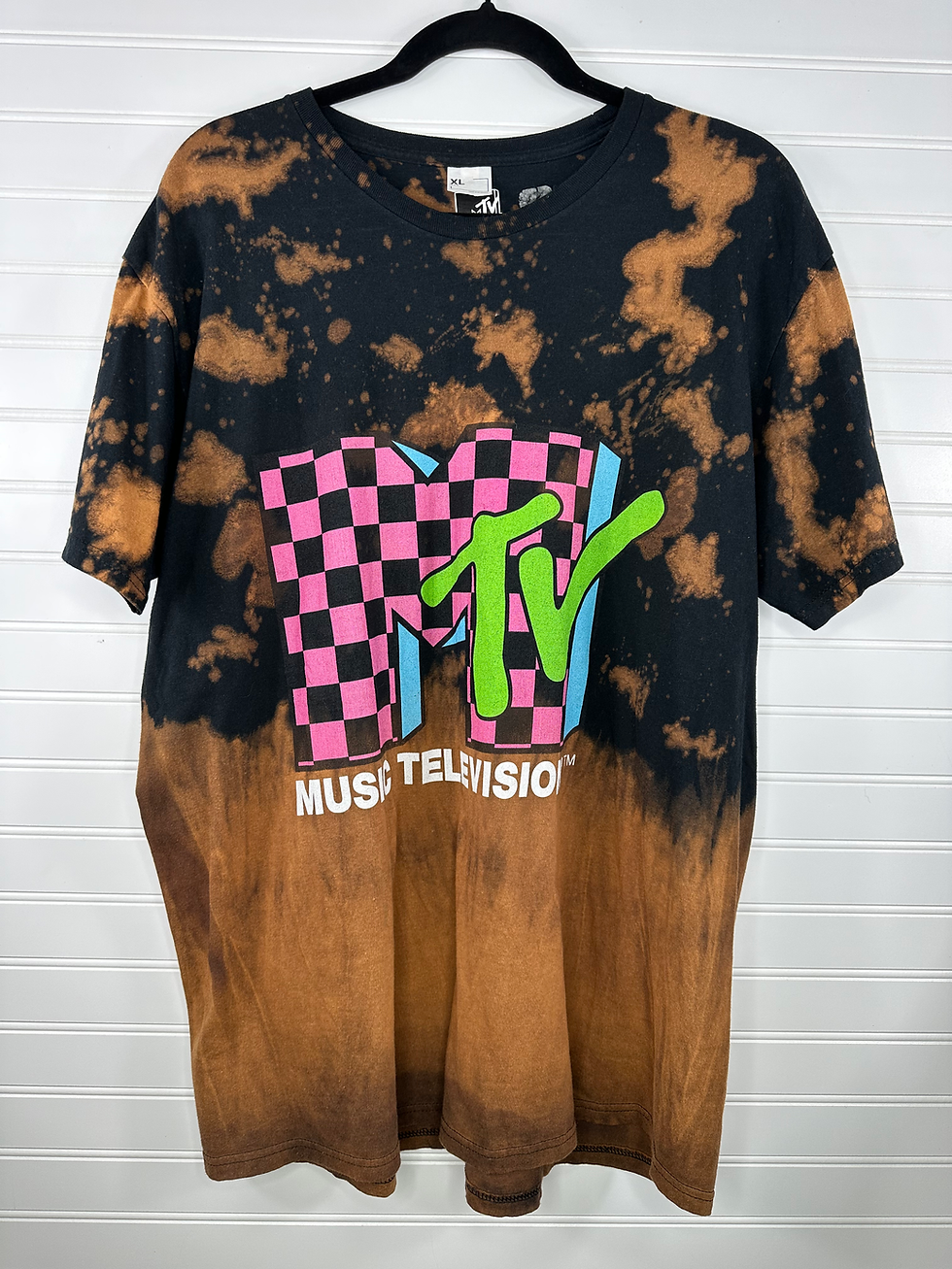 Checkered MTV graphic on front of black t-shirt with bleach splatter 